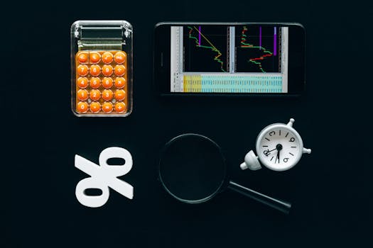 Top view of business tools including a calculator, smartphone with charts, magnifying glass, and clock on black background.