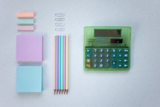 Flat lay of pastel stationery including a colorful calculator and pencils.