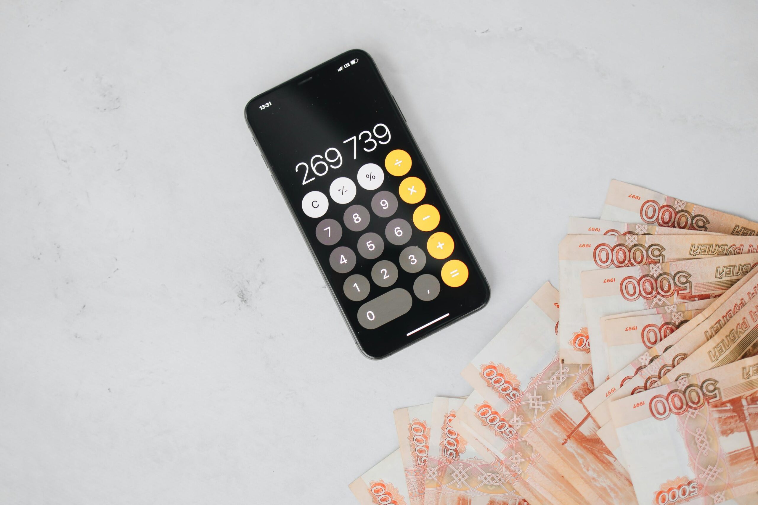 Smartphone displaying calculation with Russian rubles on a marble surface, representing finance and budgeting.